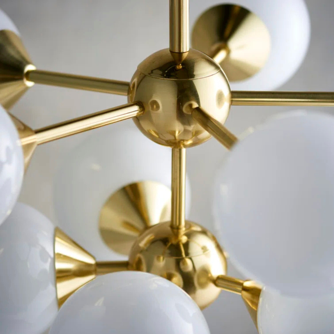 Gold chandelier with white spherical lights on a neutral background