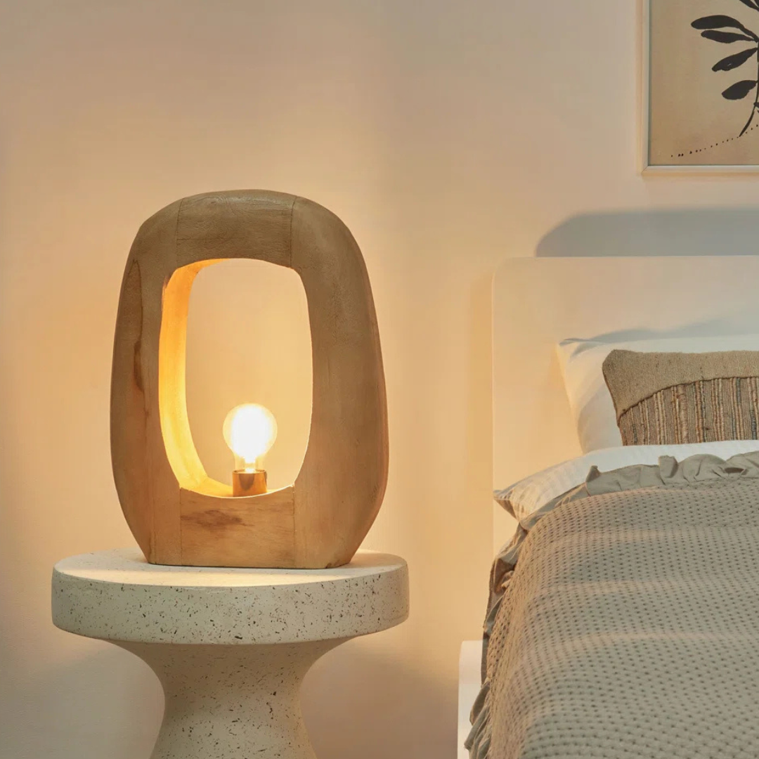 Modern concrete table lamp on a bedside table with a softly lit room.