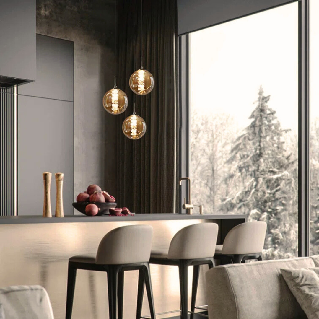 Modern kitchen with pendant lights, window view of trees, and bar stools.