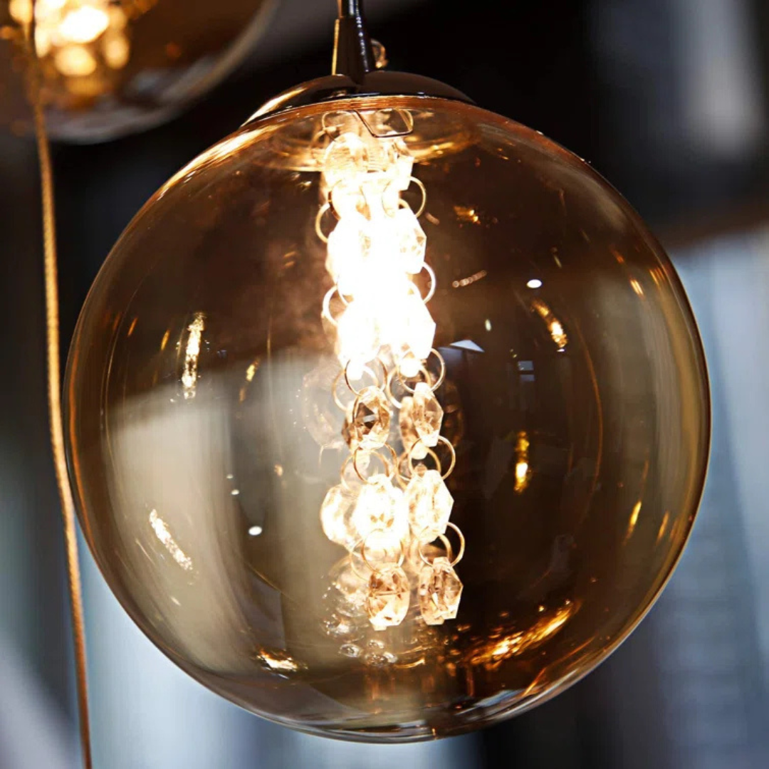 Glowing light bulb inside a transparent brown glass shade against a blurred background