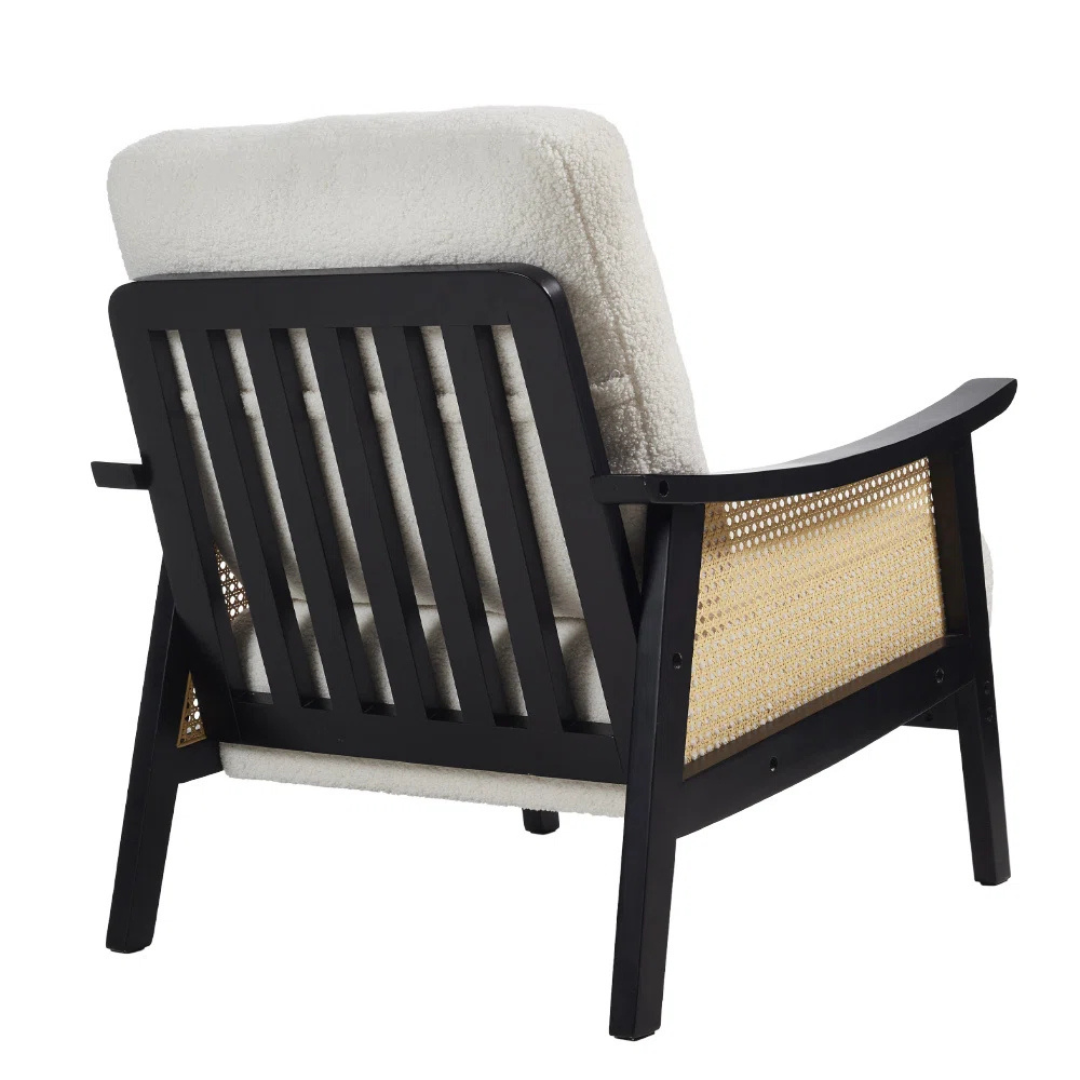 black indoor rattan armchair with curved open weave design, white background, back view.