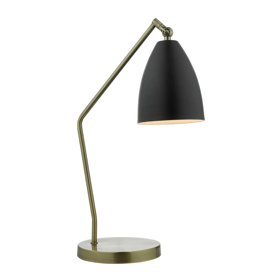Table lamp with black shade and gold arm on a white background