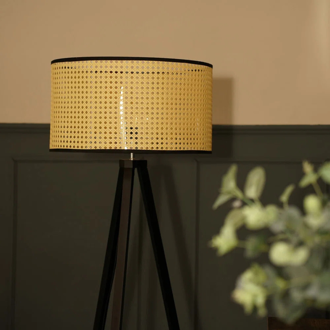 Lamp with wicker shade on a dark surface against a beige wall