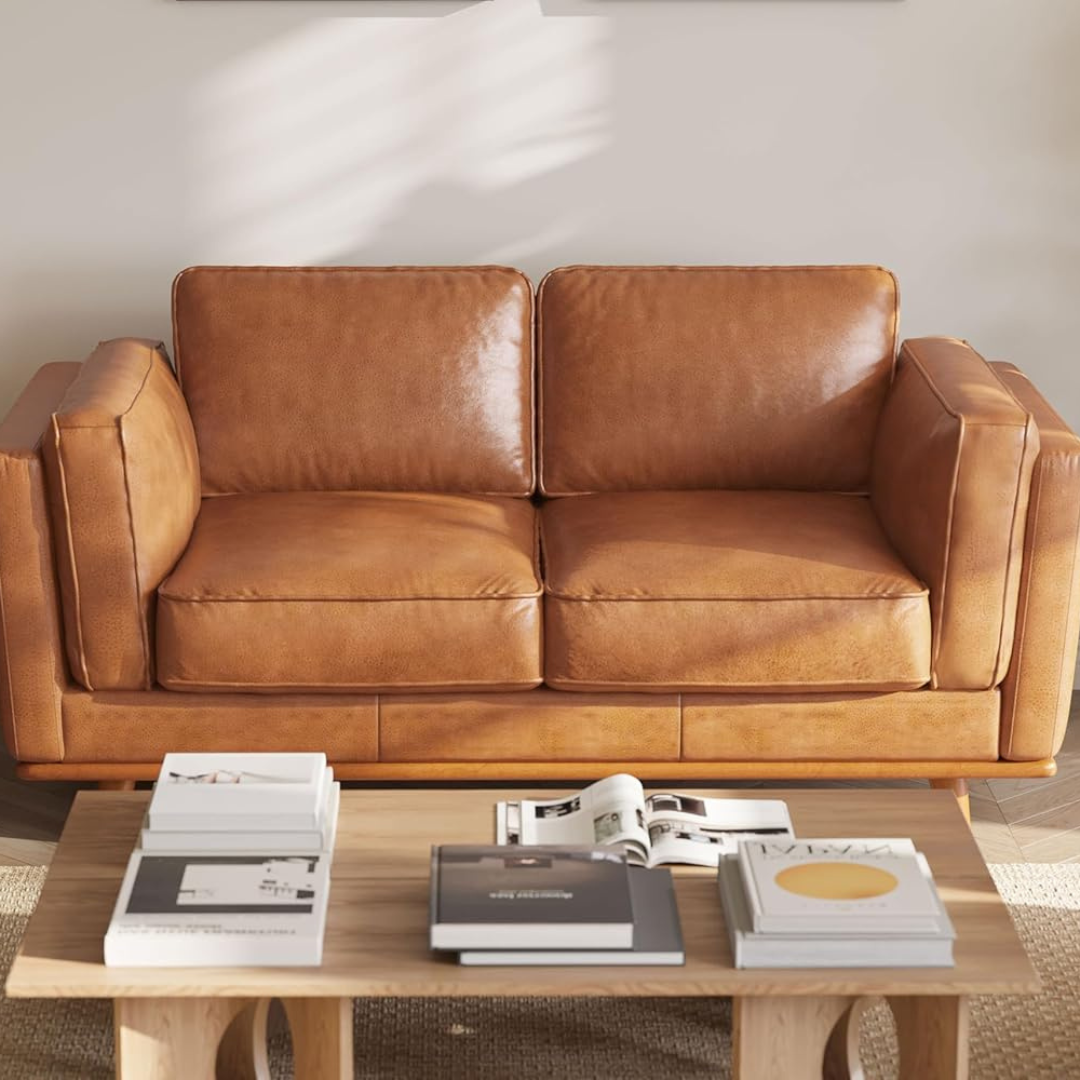 Brown leather sofa with a wooden coffee table featuring books in a living room setting.