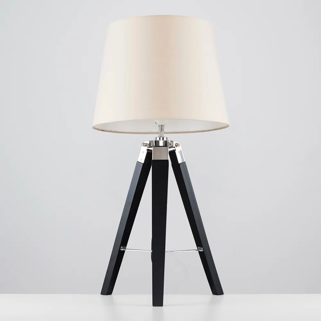 Table lamp with a white shade and black tripod base on a light gray background