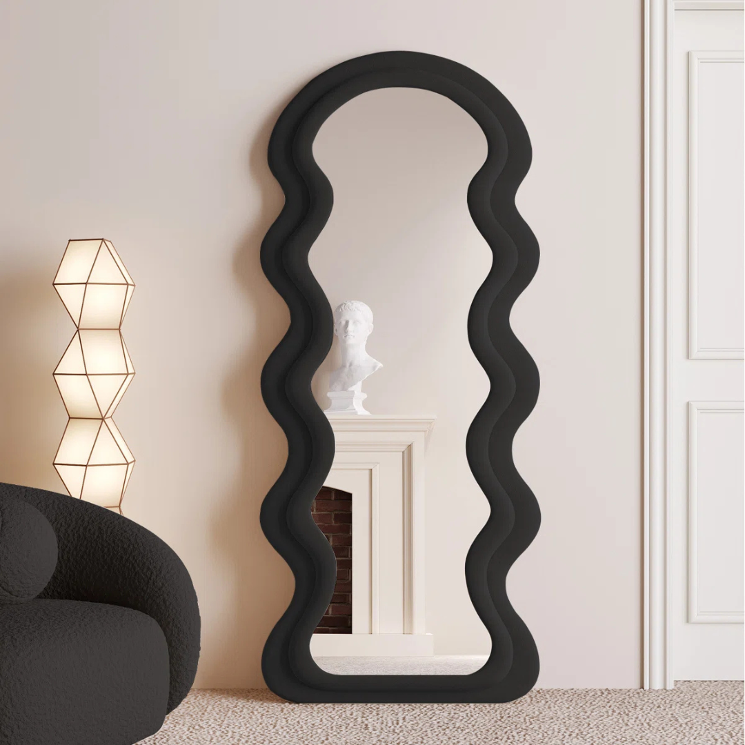 Black wavy mirror in a room with a lamp and chair.