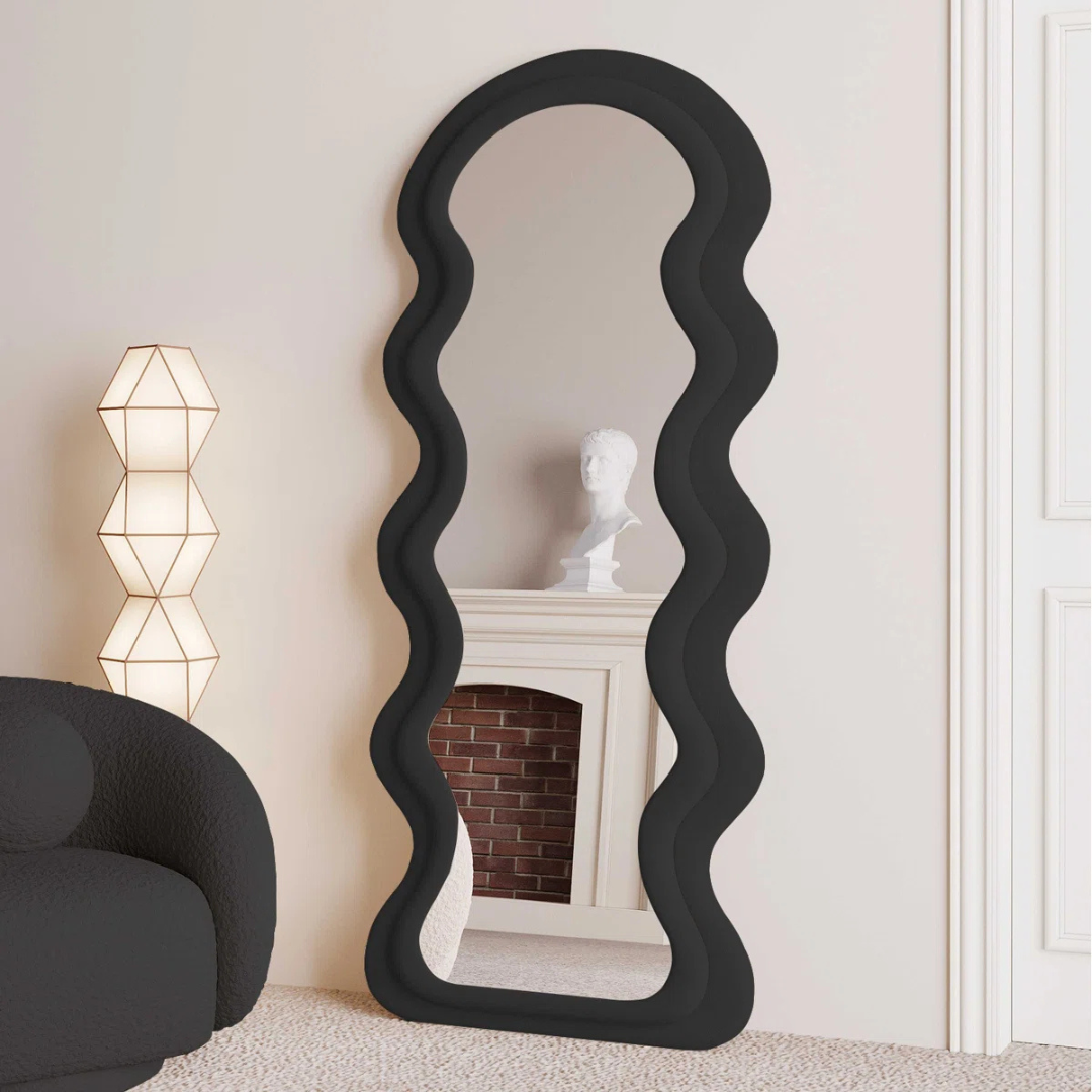 Black wavy mirror in a room with a lamp and sculpture