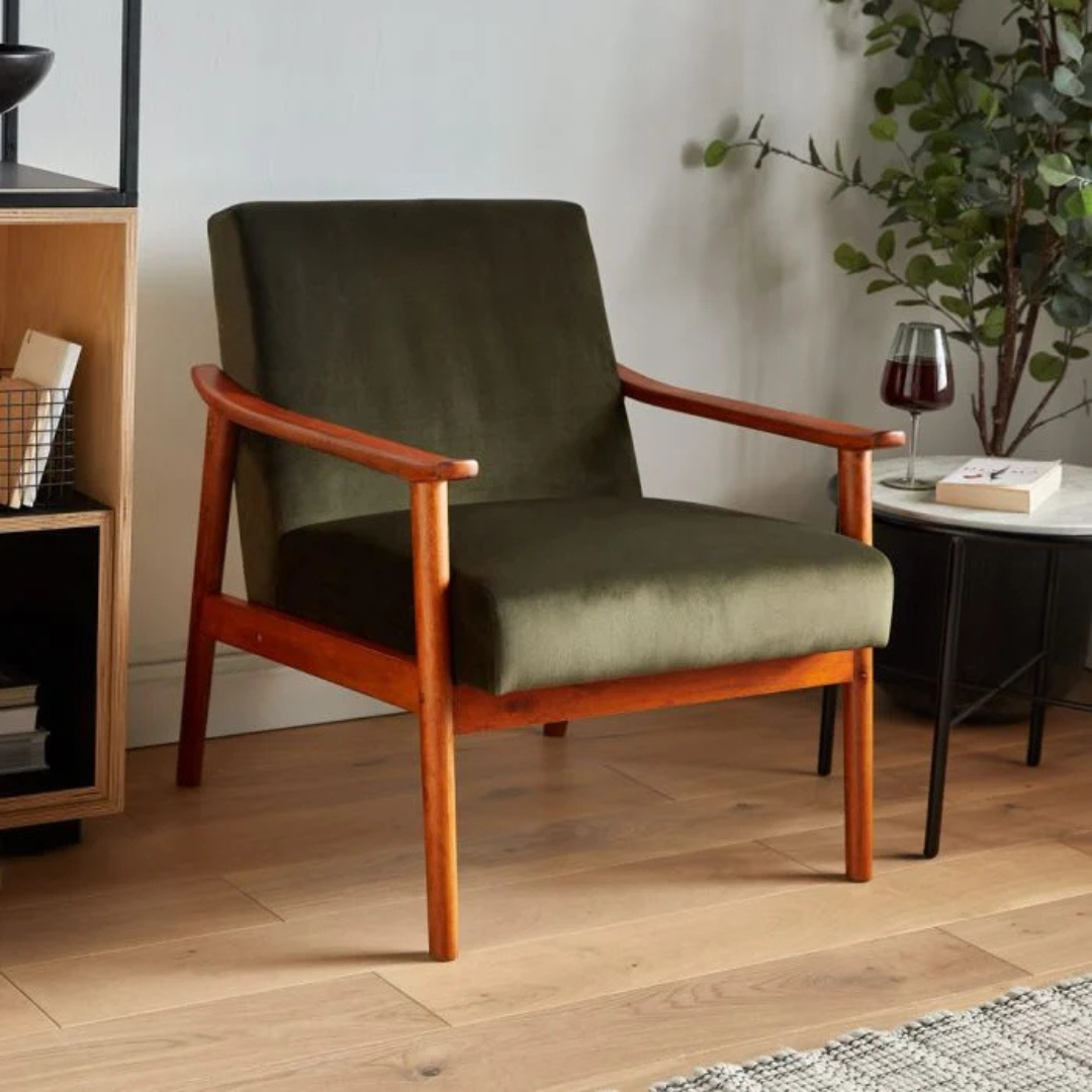 A olive green velvet armchair in a mid century living room, Angled View