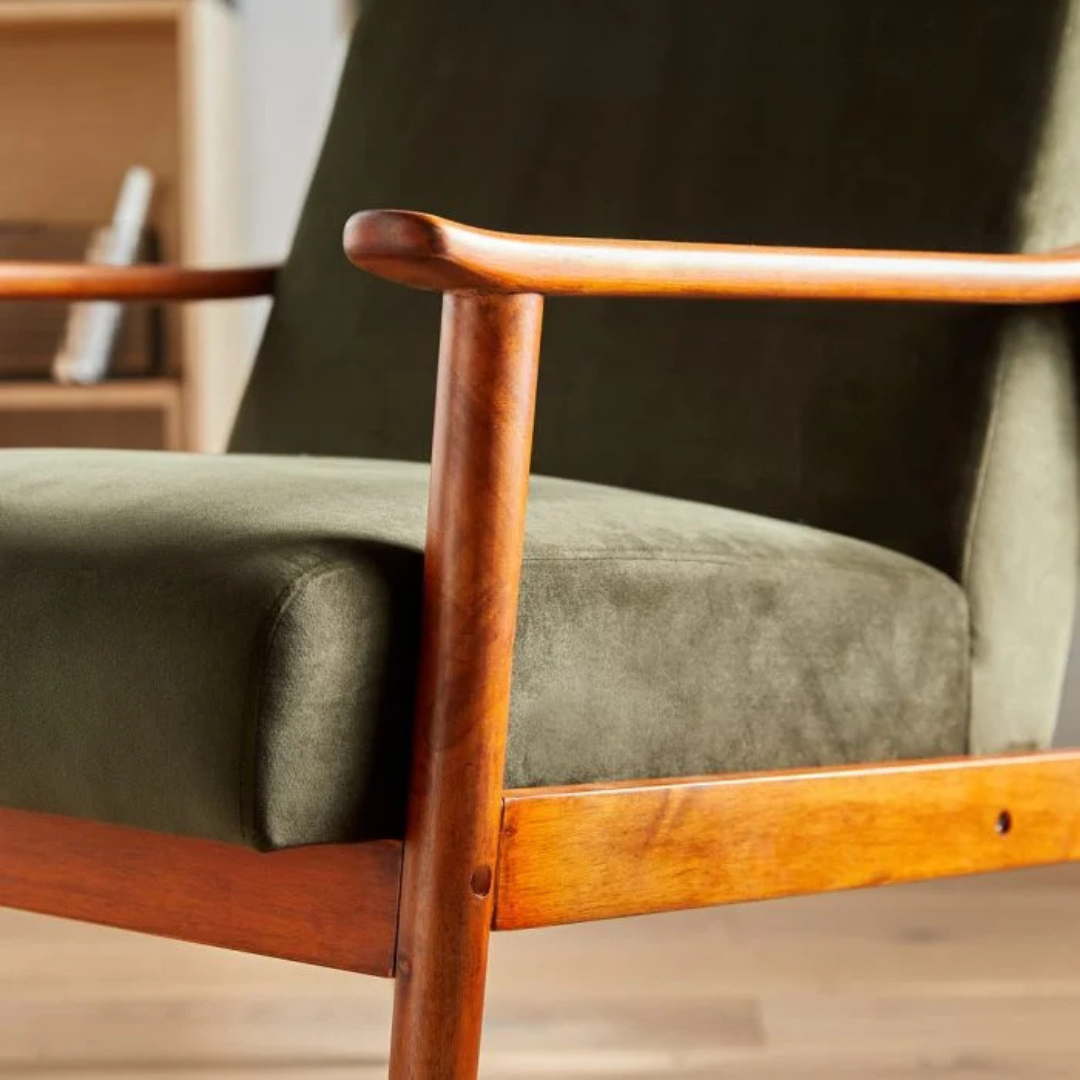 Close up of the wooden frame on the olive green velvet chair.
