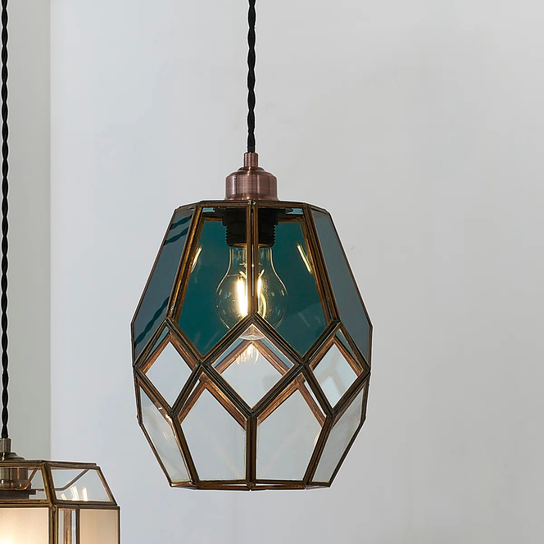 Geometric glass pendant light with brass accents on a plain background