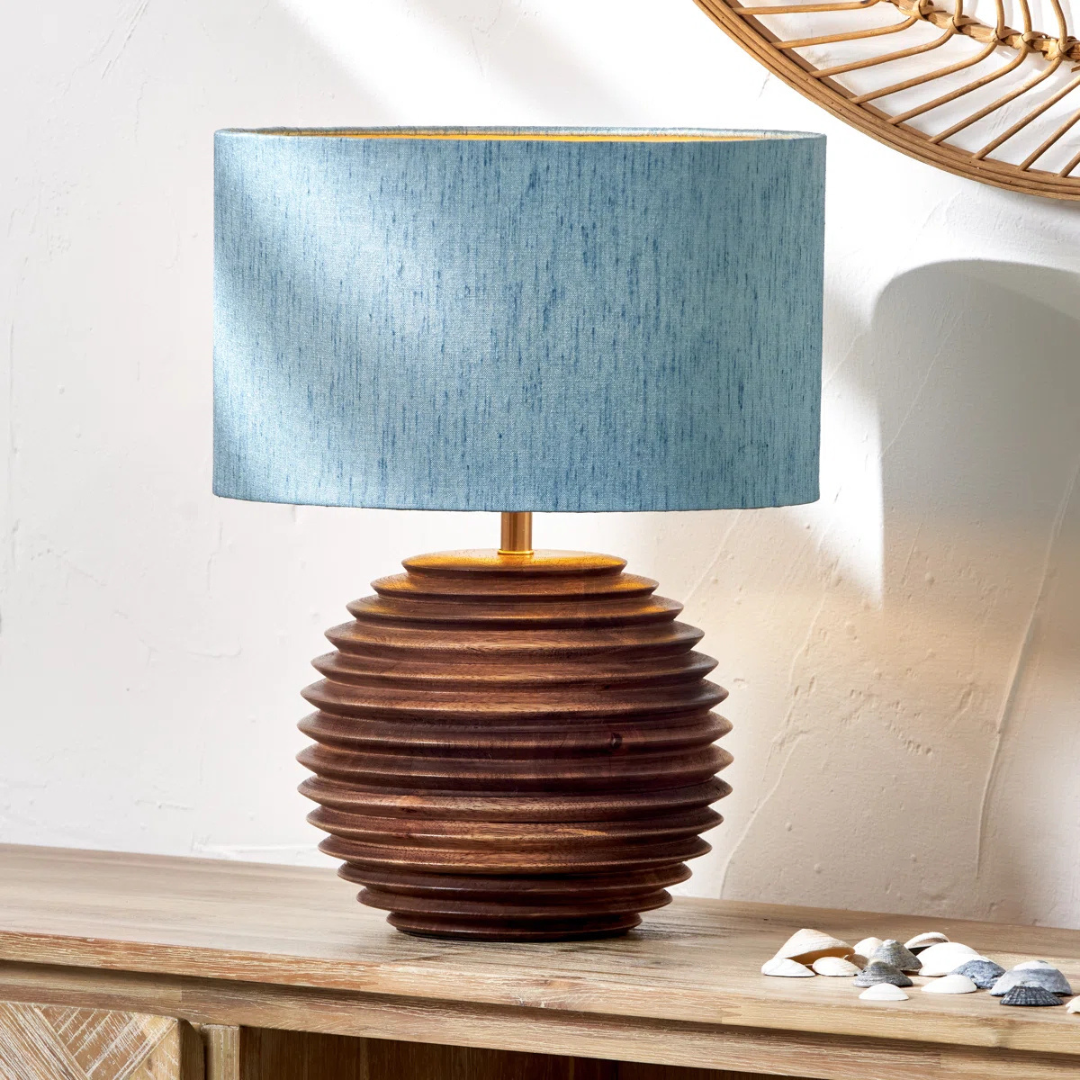 Table lamp with wooden base and blue fabric shade on a wooden surface.
