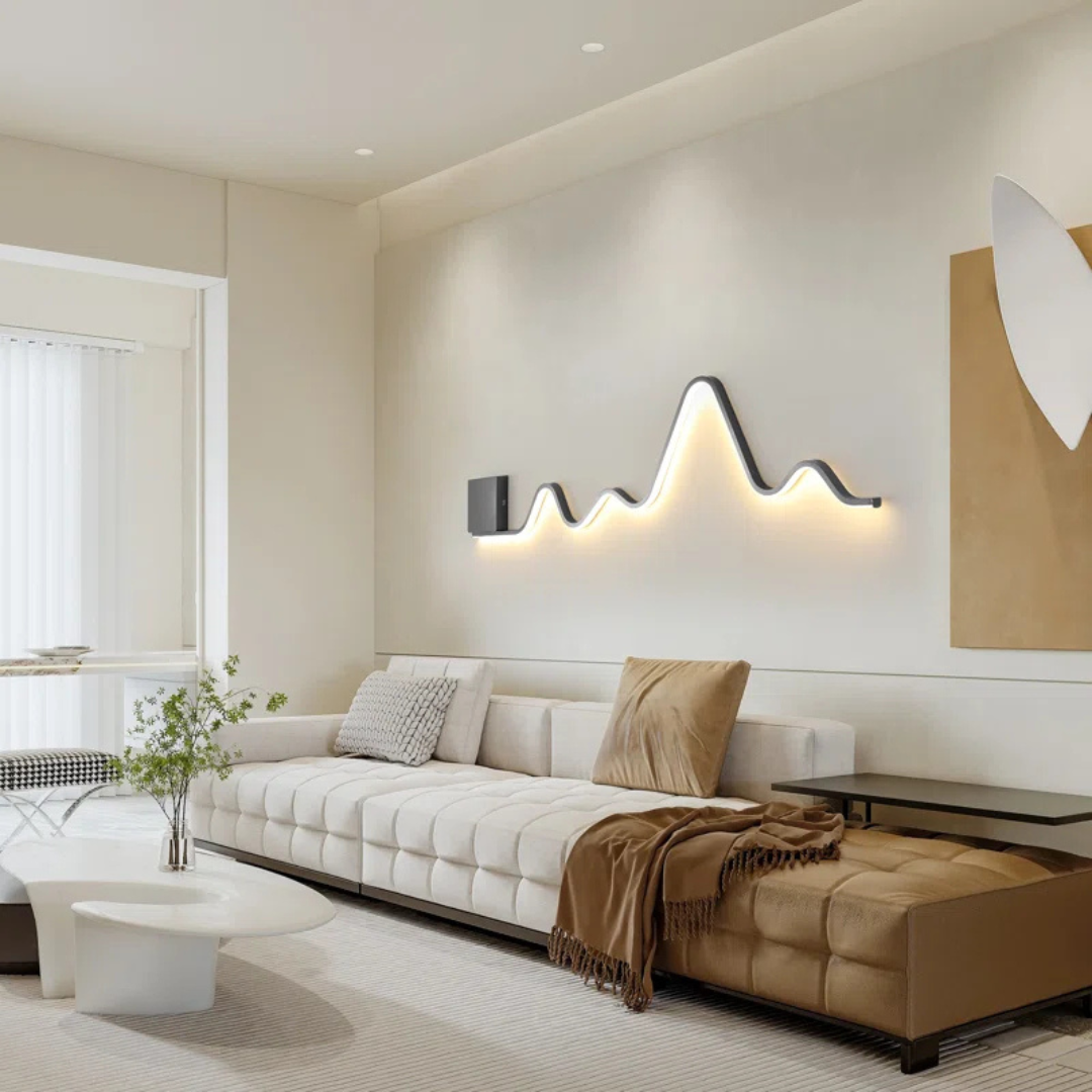 Modern living room with a white sofa, beige ottoman, and decorative wall light.