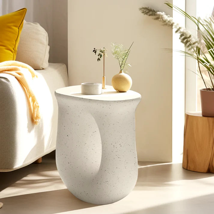 White abstract side table with cut-out design, set in a light coloured modern home.