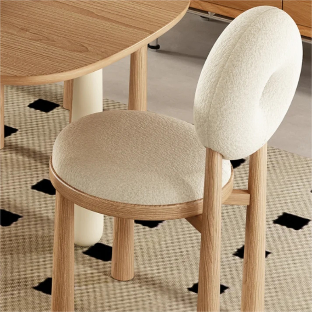 white boucle dining chair with curved back and soft seat, close up of boucle fabric. Chair is sat around a dining table.