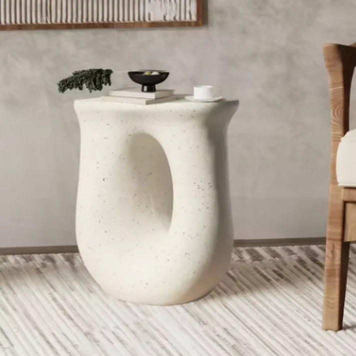 White abstract side table with cut-out design, set in a grey modern home.