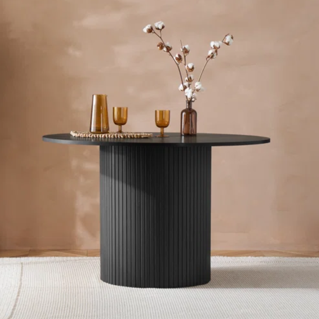 Modern black dining table with decorative items against a beige wall