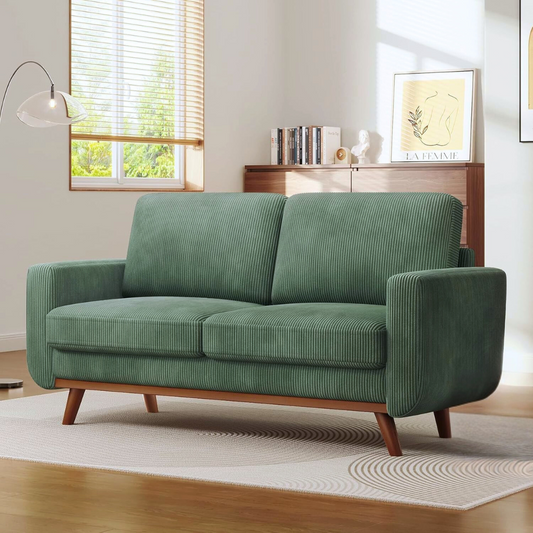 Green sofa in a living room with a window and decor in the background