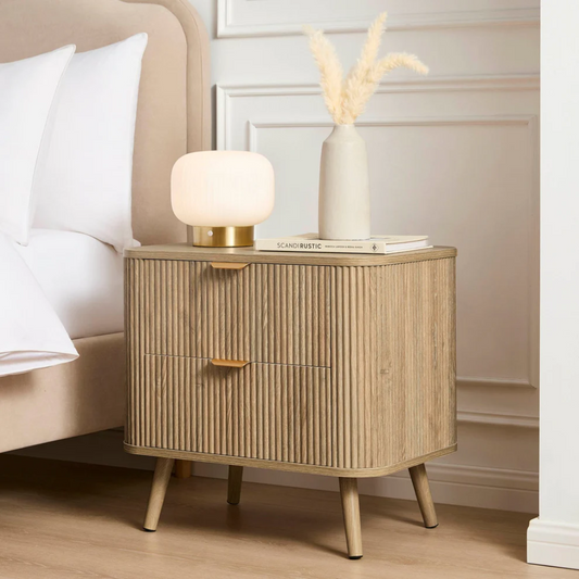 Wooden nightstand with lamp and vase in a bedroom setting