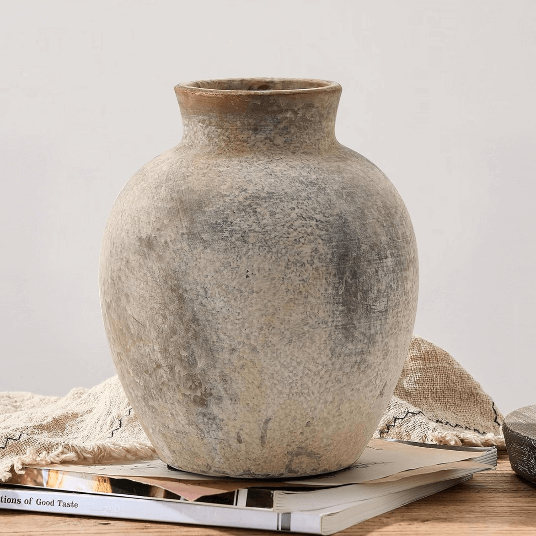 Vintage-style terracotta vase on a stack of books with a neutral background