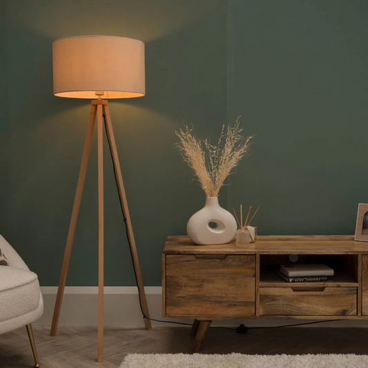 Wooden floor lamp and sideboard with decorative items against a green wall.