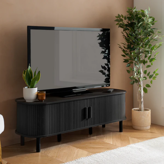 Black TV stand with a television and decorative items in a room with plants.