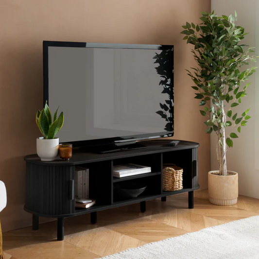 Black TV stand with a television, plants, and decorative items in a room.