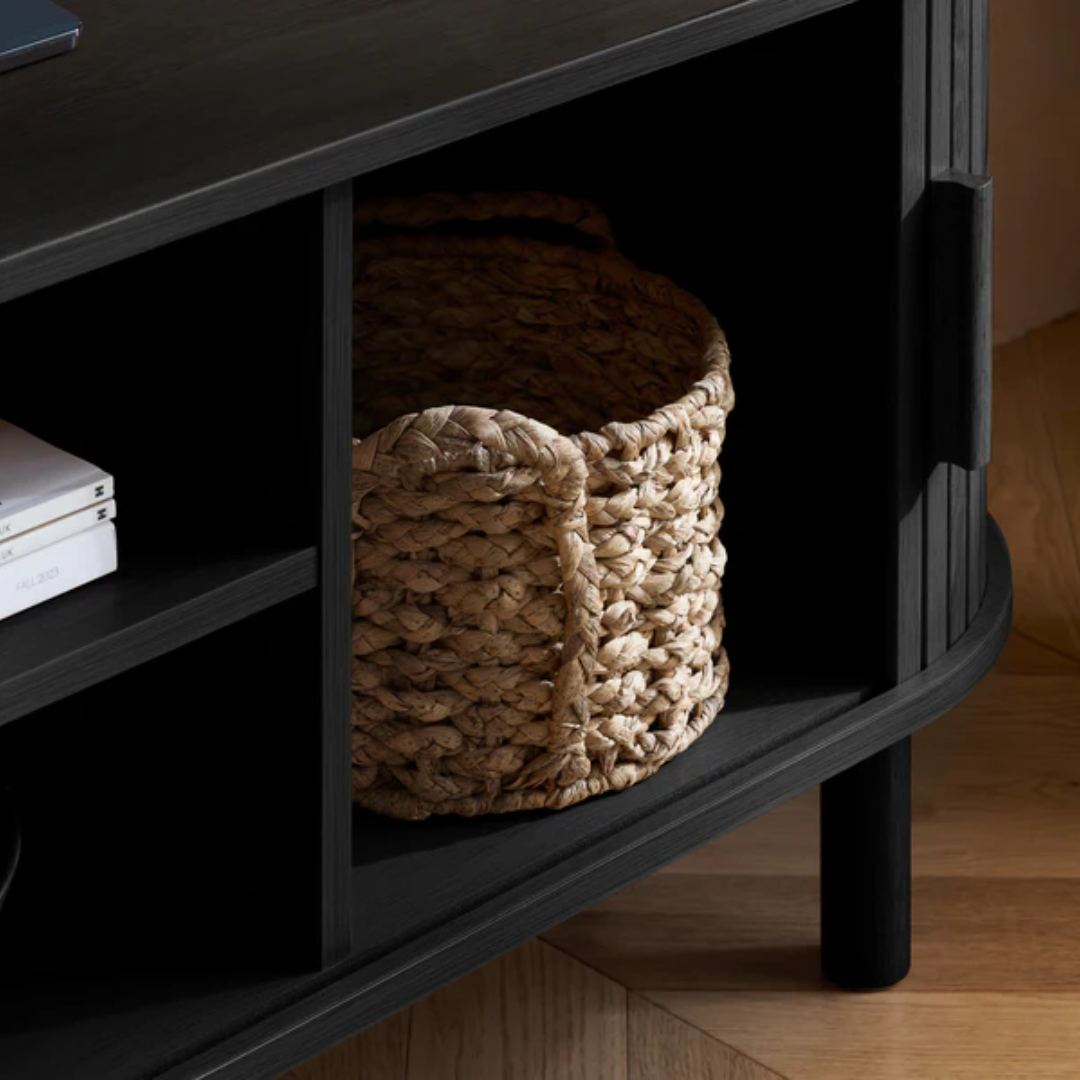 Woven basket on a black shelf with books in a room setting