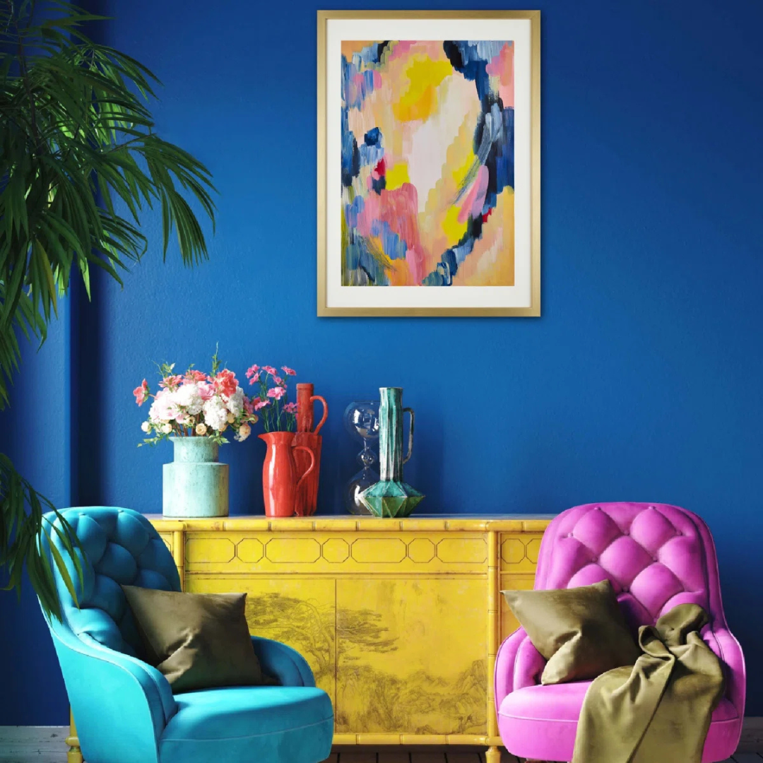 Colorful living room with blue and pink chairs, yellow cabinet, and abstract art on a blue wall.