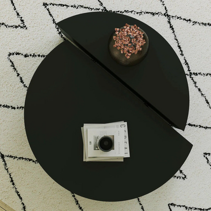 Contemporary low round coffee table with magazine slot, black table, top view.