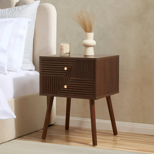Walnut Wooden bedside table with a candle and decorative vase next to a bed.
