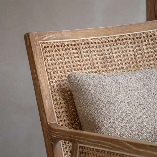Close-up of a wooden chair with woven backrest and gray cushion on a neutral background