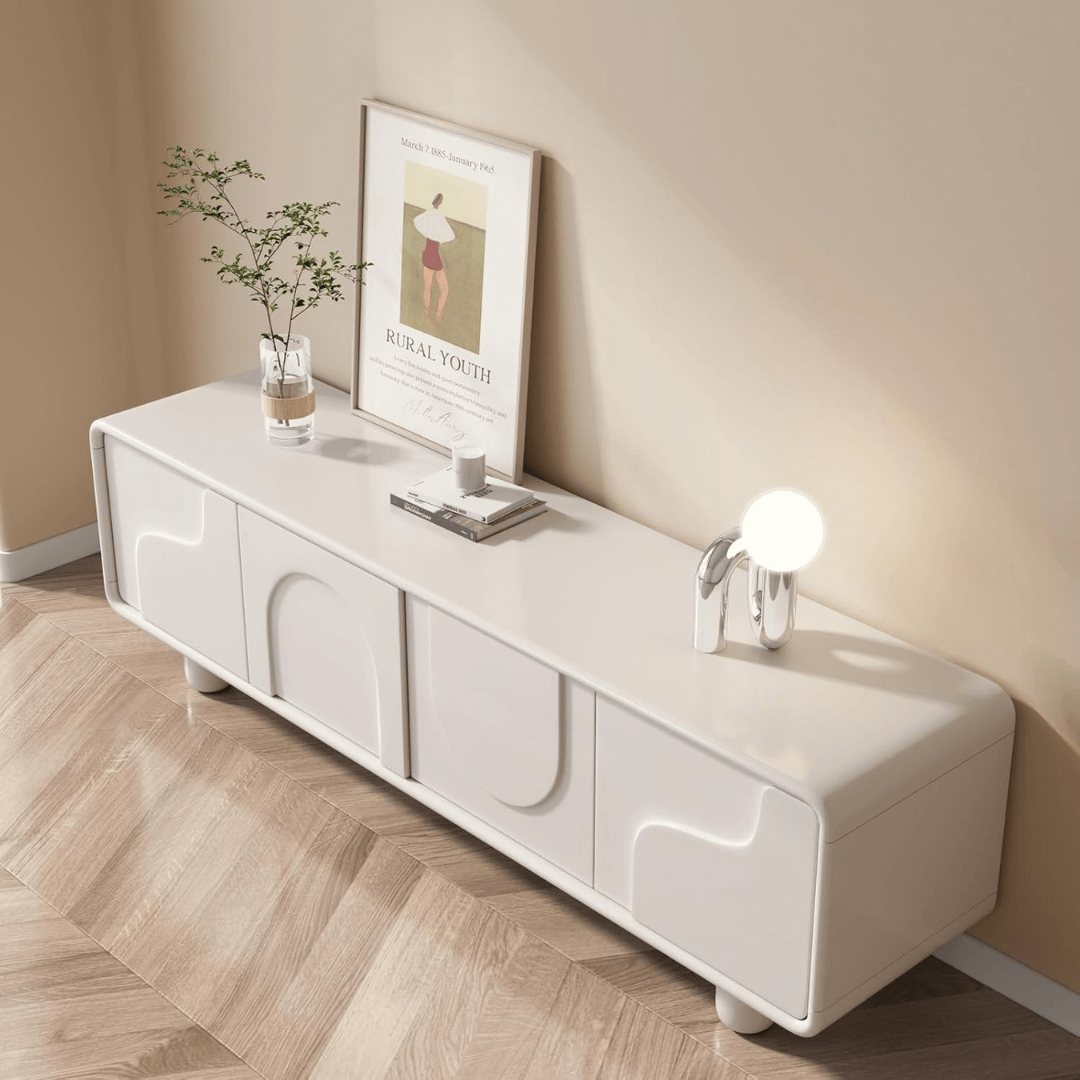 White entertainment console with decorative items against a beige wall.