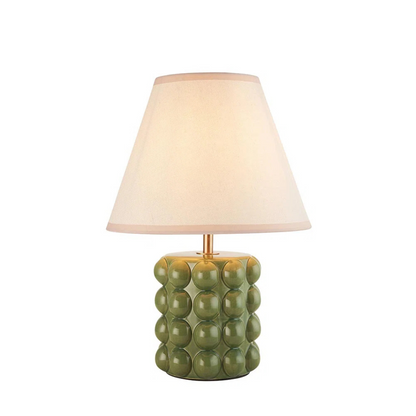 Table lamp with green textured base and beige shade on a white background