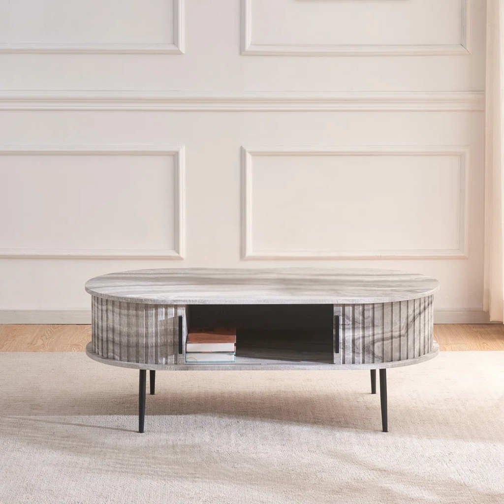 Grey marble effect oval coffee table with fluted base, in a modern home, with the doors open.