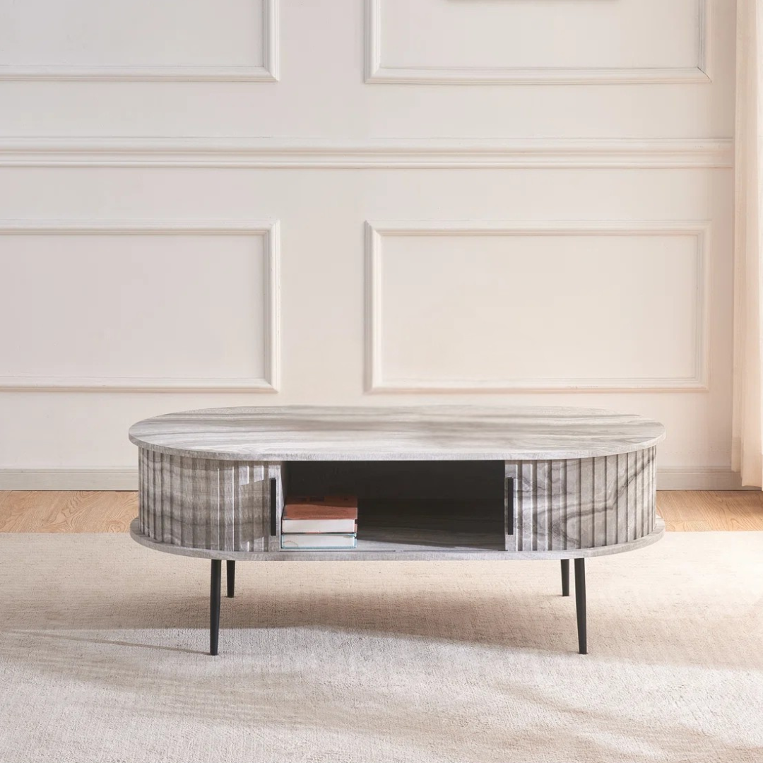 Grey marble effect oval coffee table with fluted base, in a modern home, with the doors open.