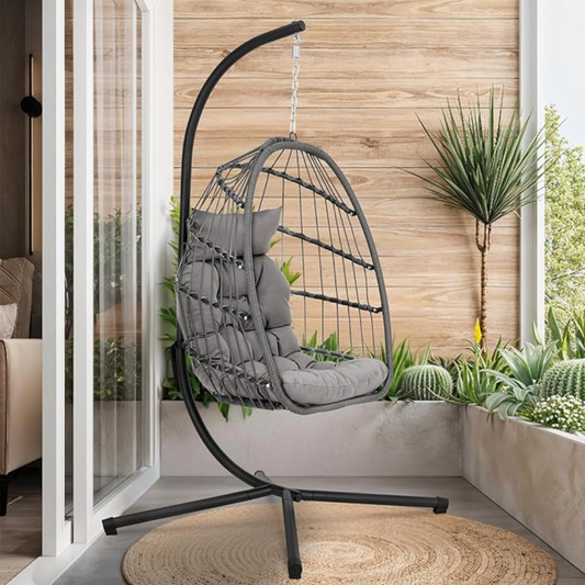 Grey Rattan Hanging Egg Chair And Stand set on an outdoor balcony.