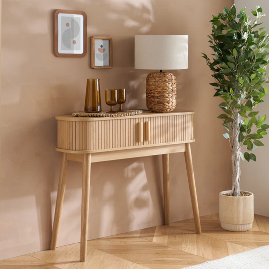 Wooden console table with decorative items against a beige wall.