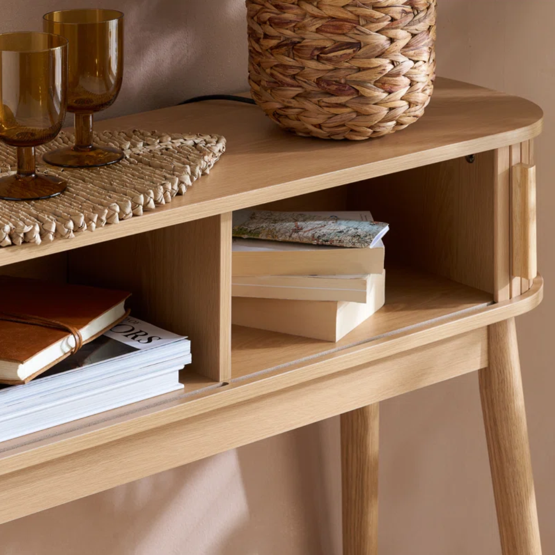 Wooden shelf with books, a woven basket, and glasses on a neutral background