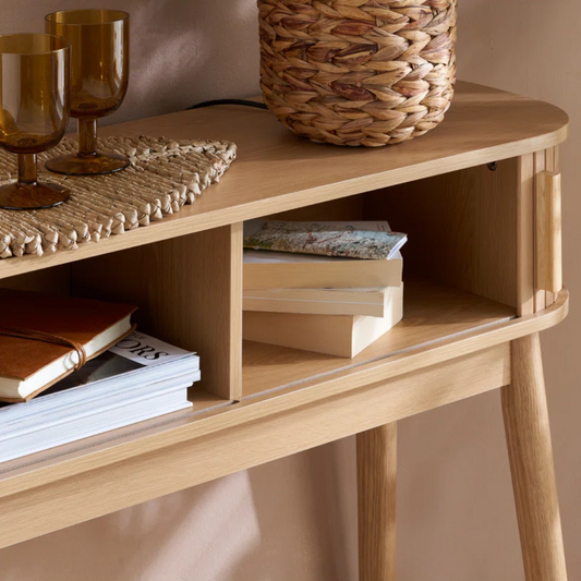 Wooden shelf with books, a woven basket, and glasses on a neutral background