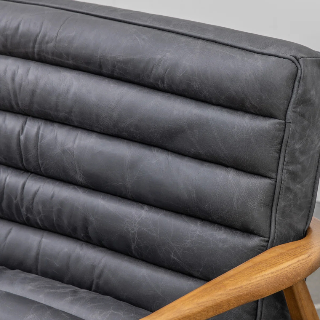Gray leather armchair with wooden armrests on a neutral background