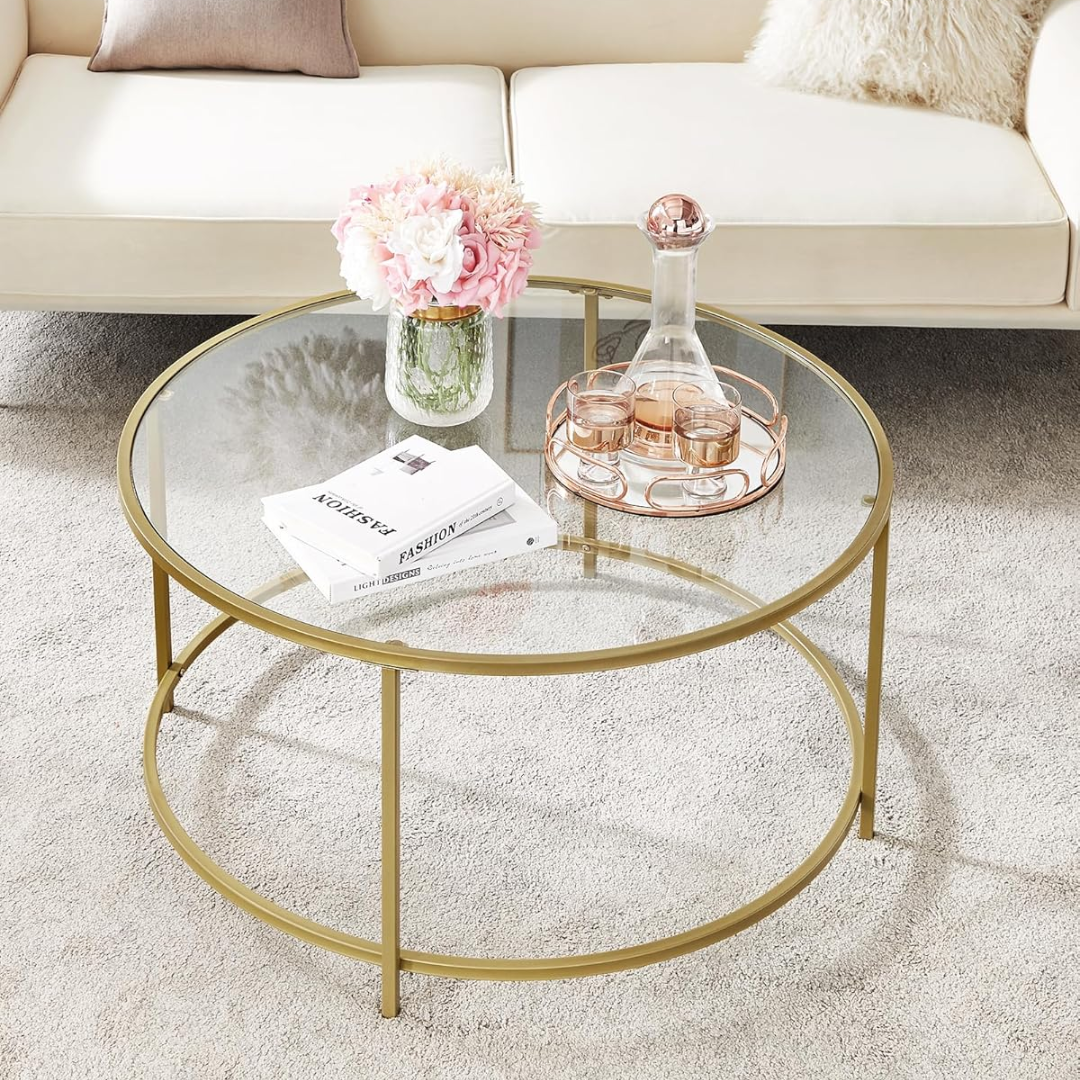 Round glass coffee table with gold metal frame in a living room setting.