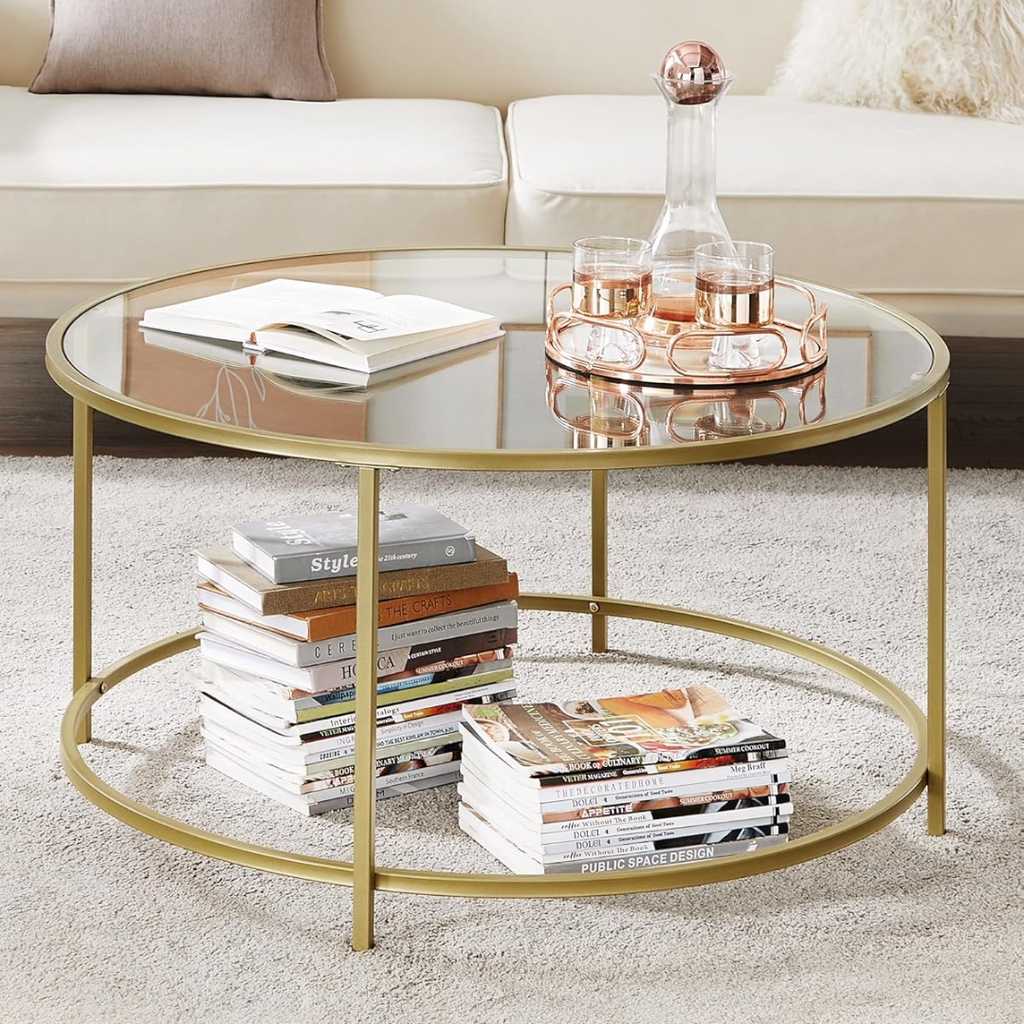 Round gold coffee table with books and a glass on a carpeted floor.