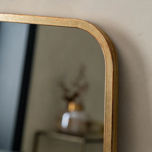 Gold-framed mirror on a beige wall