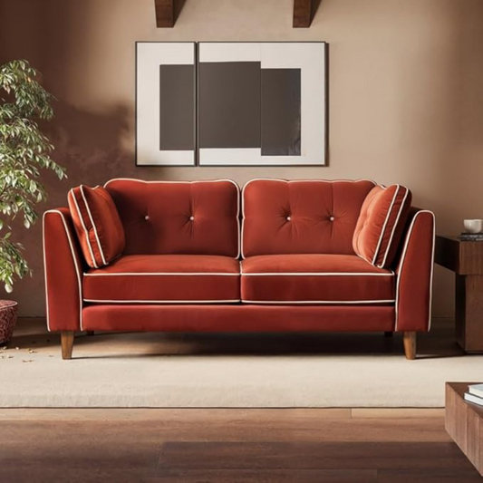 Red velvet sofa in a living room setting with a painting on the wall.