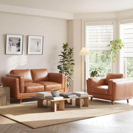 Modern living room with brown leather sofa and armchair, coffee table, and large windows.