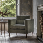 Green armchair in a room with a window and fireplace