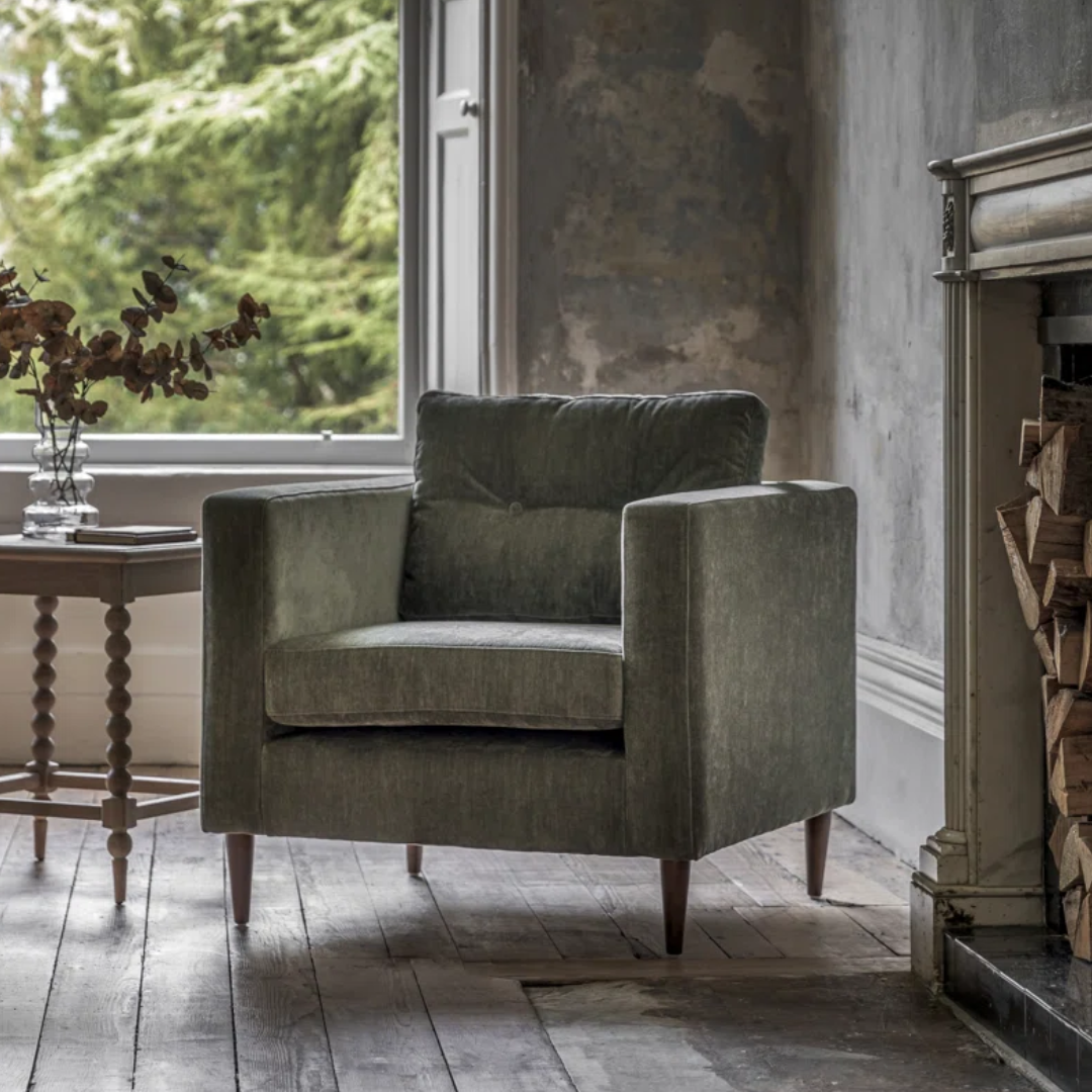 Green armchair in a room with a window and fireplace