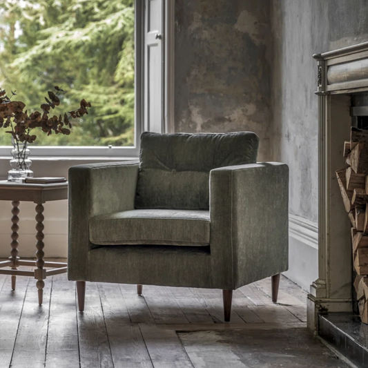 Green armchair in a room with a window and fireplace