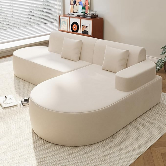 Beige sectional sofa in a living room setting with a window and decorative items in the background.
