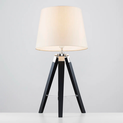 Table lamp with a white shade and black wooden base on a light gray background